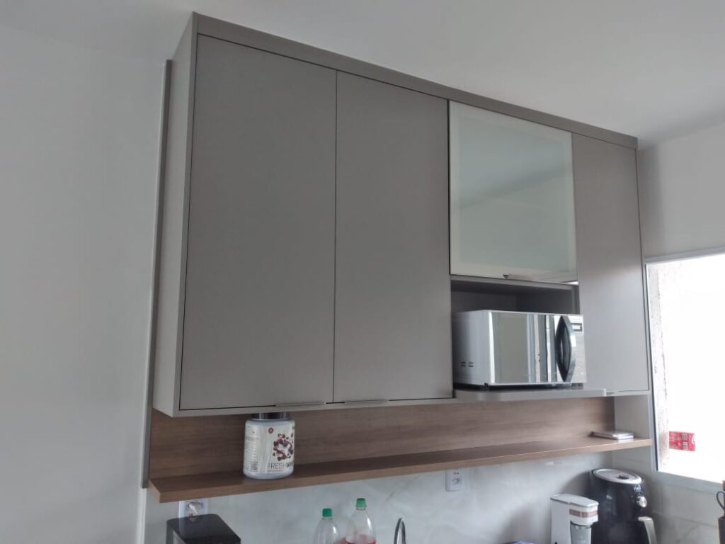 Cozinha planejada com bancada em L e armários amadeirados, projeto Kless em Sertãozinho